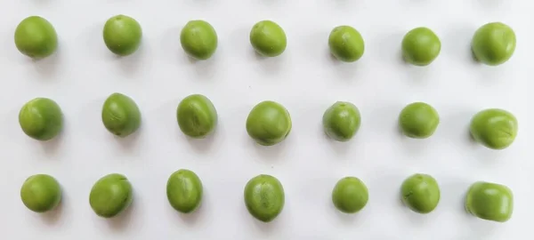 Bezelyeler sıraya dizildi. Pisum sativum. Genç bezelyelerle patlayan taze, canlı bezelye kabuklarının yakın çekimi, beyaz arka planda güzelce düzenlenmiş. Bu hassas ve besleyici baklagiller gerçek bir yaz sevinci.