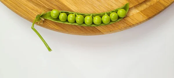 Bezelye kabuğu beyaz arka planda kompartıman plakası. Pisum sativum. Genç bezelyelerle patlayan taze, canlı bezelye kabuklarının yakın çekimi, beyaz arka planda güzelce düzenlenmiş. Bu hassas ve besleyici baklagiller gerçek bir yaz sevinci.