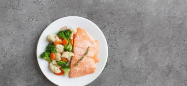 Bahçe sebzeli, besin zengini haşlanmış somon balığı.