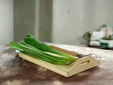 Taze yeşil sebzeler beyaz bir arka planda güzelce dizilmiş.