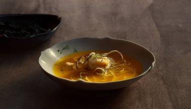Sarı bir kasede taze pişmiş deniz ürünleri çorbası..