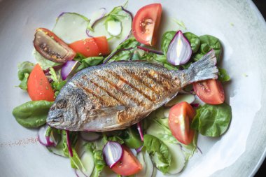 Izgara yaldızlı baş çipura, roka ile süslenmiş.