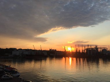 Riga limanında gün batımında, arkasında bir gemi ve bir nehir var.