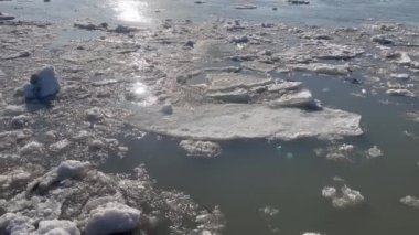 Video, ilkbaharda nehirde eriyen buzları yakalıyor. Büyük buz blokları suda tamamen eriyene kadar akıntı yönünde yavaşça yüzerler. Kamera ufukta beliriyor.
