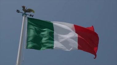 Güneşli bir günde ağır çekimde rüzgarda dalgalanan büyük İtalyan bayrağı. Yüksek kalite 4k görüntü