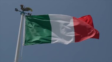 Güneşli bir günde ağır çekimde rüzgarda dalgalanan büyük İtalyan bayrağı. Yüksek kalite 4k görüntü