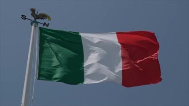 Güneşli bir günde ağır çekimde rüzgarda dalgalanan büyük İtalyan bayrağı. Yüksek kalite 4k görüntü