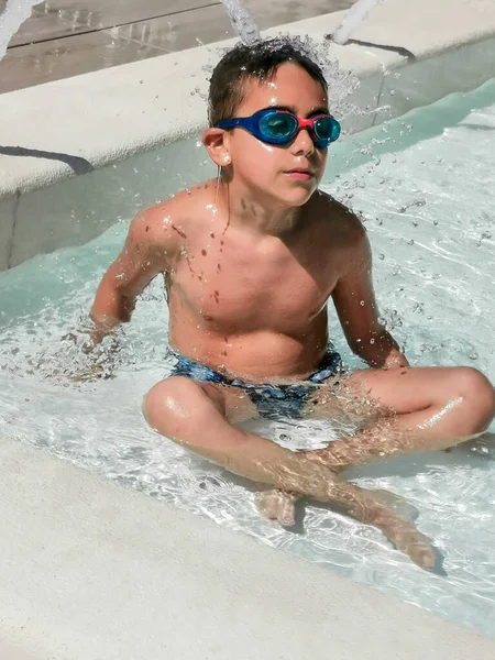 child with swimming goggles plays in the water. High quality photo