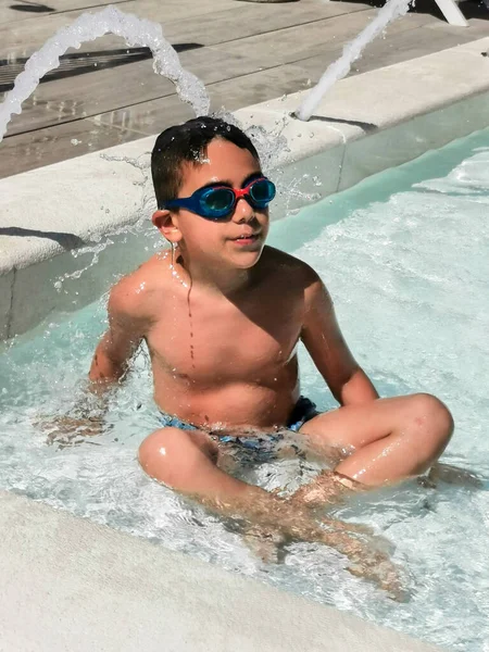 child with swimming goggles plays in the water. High quality photo
