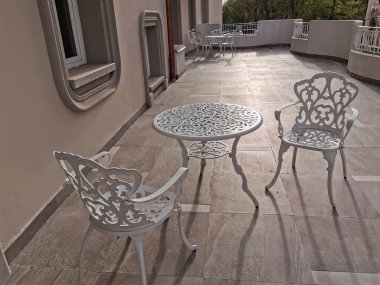 white wrought iron table and chair with floral motifs on terrace at dawn. High quality photo