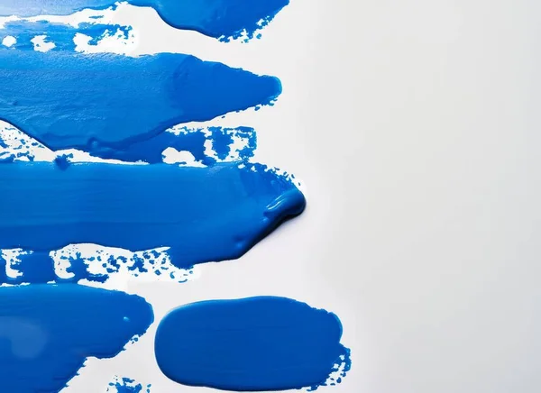 Close up of blue paint shapes on white background with copy space. High quality photo