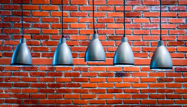 Many pendant lamps against red old brick wall. High quality photo