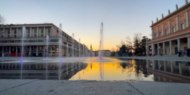 Reggio Emilia Piazza della Vittoria, gün batımındaki çeşmenin yansıması. Yüksek kalite fotoğraf