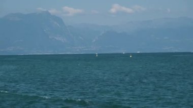 Peschiera sahilinden Garda Gölü, güneşli bir günde, uzaktaki teknelerle panorama. Yüksek kalite 4k görüntü