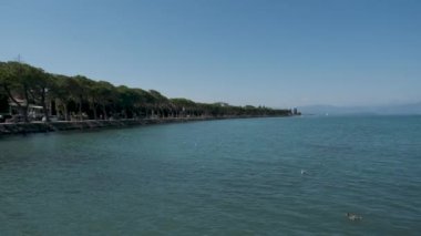 Peschiera sahilinden Garda Gölü, güneşli bir günde, uzaktaki teknelerle panorama. Yüksek kalite 4k görüntü