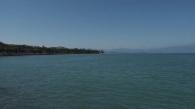 Peschiera sahilinden Garda Gölü, güneşli bir günde, uzaktaki teknelerle panorama. Yüksek kalite 4k görüntü