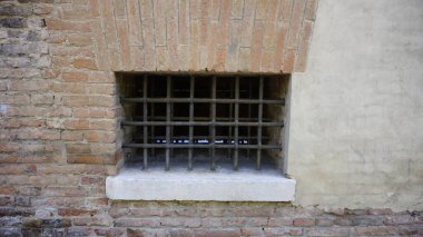 Metal parmaklıkların demirden yapıldığı sağlam bir tuğla duvar bina cephesinde kompozit malzeme kullanımını gösteriyor.