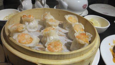 Karides köftesiyle dolu bambu bir buhar tenceresi, lezzetli bir konforlu yiyecek bulaşık takımı, masada oturuyor ve tarifte kullanılan taze deniz ürünlerini gösteriyor.