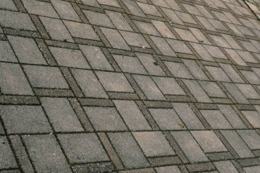 Çapraz desenli dikdörtgen gri tuğlalı bir geçitin detaylı bir görüntüsü, bileşik malzemelerden yapılmış bir binanın zeminine benziyor.