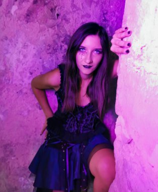 Bir kadın canlı mor bir duvarın önünde fener tutuyor ve sahneye eflatun bir dokunuş ekliyor. Flaş fotoğrafçılık, sahne sanatları temasını vurgulayarak anı yakalıyor.