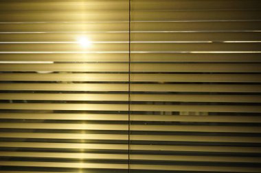 Güneşin altın ışınları ahşap pencerenin kehribar gölgelerinden süzülüyor. Güzel bir ışık ve gölge deseni yaratıyor.