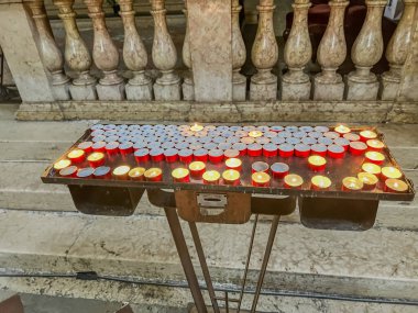 Kilisedeki ahşap bir masanın üzerine kırmızı mumlar dizilir ve etkinlik için sıcak ve davetkar bir ortam yaratır.