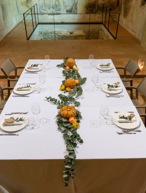 Balkabakları, yapraklar ve çiçeklerle süslenmiş güzel bir masa. Doğal yiyecekler ve mevsimlik malzemelerle dolu bir yemek için mükemmel bir ortam.