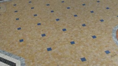 Milano tahılını andıran bej ve kahverengi desenli fayanslı zeminin yakın çekimi. Döşeme malzemesi asfalt yol yüzeyini anımsatıyor.