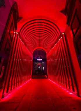 Milan,Italy : 10 11 2023 The tunnel glows with red lights on walls and ceiling, forming a visually striking effect. Symmetrical red and magenta lighting serve as a landmark, enhancing the architectural design clipart