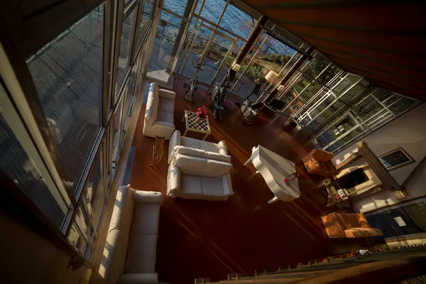 stock image An aerial view from above shows a living room overlooking a body of water, featuring a boat and wooden architecture. The scene captures a sense of leisure and watercraft on the hardwood floor