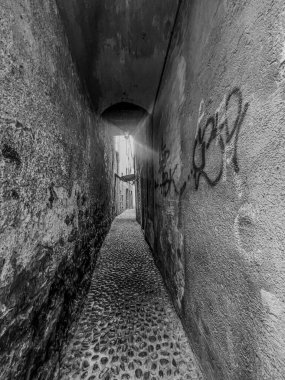 Yıpranmış duvarlar boyunca uzanan canlı graffitilerle süslenmiş iki bitişik binanın arasına kurulmuş dar bir sokak.