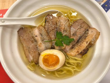 Lezzetli ramen çorbasıyla dolu lezzetli bir kase içinde taze et ve erişte var, içinde de bir kaşık dinleniyor.