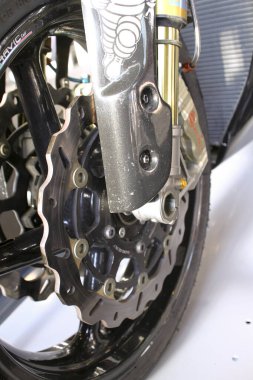 Bu, güvenlik ve performans için gerekli olan, motorsiklet ön disk fren sisteminin karmaşık dizaynını ve bileşenlerini gösteren detaylı bir yakın çekim görüntüsü.