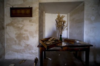 Güzel dekore edilmiş bir odada, yüzeyinde hayat dolu çiçeklerle dolu güzel bir vazo bulunan cilalı bir masa var.