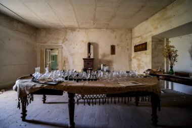 Boş ve ferah bir oda. Yüzeyinde birkaç bardak bulunan bir masa.