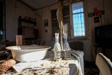 Odada iki şişeyle birlikte üzerine bir kase konmuş bir masa var. Büyüleyici bir ortam yaratıyor.