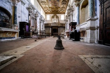 Mimarinin ihtişamıyla çevrili boş ve sessiz bir kilisenin tam ortasında huzur içinde bir çan duruyor.