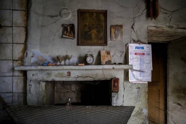 Odanın ortasında, çok güzel tasarlanmış bir şömine duruyor, ve üzerine tünemiş antika bir saat var.