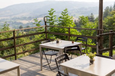 Güvertede, ziyaretçilerin uzaktaki dağların güzel manzarasının keyfini çıkarmalarına olanak sağlayan çeşitli masa ve sandalyeler var.