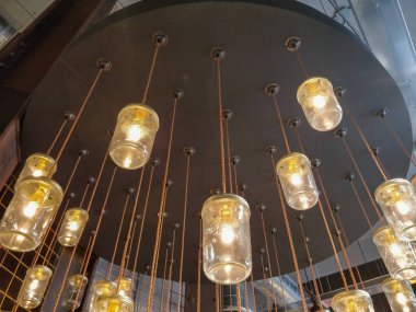 Duvardan yapılmış güzel bir kavanoz lambası koleksiyonu tavandan sarkan zarif bir şekilde odada sıcak bir ortam yaratıyor.