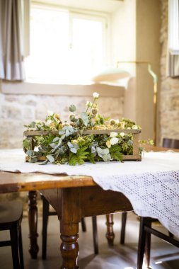 Yüzeyinde taze çiçeklerle dolu güzel bir vazoyla süslenmiş kırsal ahşap bir masa.