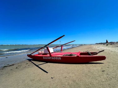 Kumsalda, dikkat çekici bir kırmızı tekne var. Salvataggio sözcüğünü açıkça gösteriyor. Bu da İngilizce 'de kurtarma anlamına geliyor.