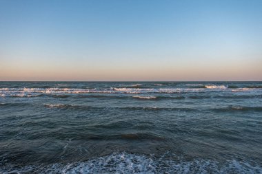 Şafak vakti Cesenatico sahilinde güneş ve yumuşak dalgalarla. Yüksek kalite fotoğraf