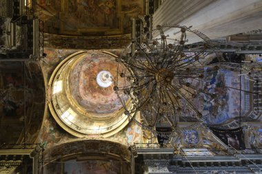 A glimpse of an ornate ceiling featuring a chandelier and a fresco, showcasing the intricate details of the interior architecture. clipart