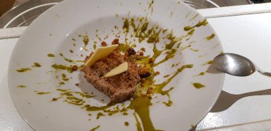 Bir dilim peynirli rulo köfte içeren görsel olarak cezbedici bir yemek, canlı yeşil sos serpiştirilmiş beyaz bir tabakta sunuluyor.