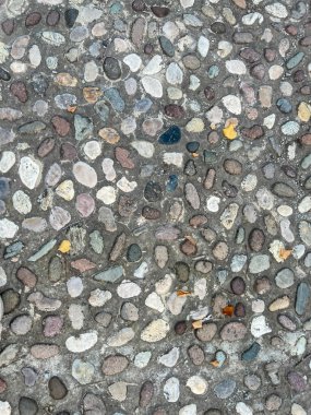 Bir çakıl taşı mozaik zemin yakın çekim, gri, beyaz ve bej renkleri değişen küçük taşların karmaşık düzenini sergiler.