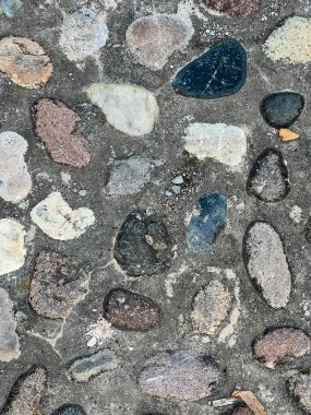 Bir çakıl taşı mozaik zemin yakın çekim, gri, beyaz ve bej renkleri değişen küçük taşların karmaşık düzenini sergiler.