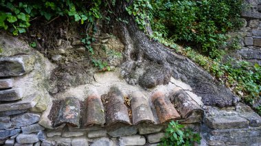 Üzerinde tuğla kemer ve yeşillik büyüyen eski bir taş duvar, mimariyle harmanlanmış doğanın güzelliğini gösteriyor..