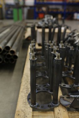 Duvarda asılı çeşitli borulardan oluşan bir koleksiyon büyük bir depo alanı içinde, farklı malzeme ve türleri sergiliyor