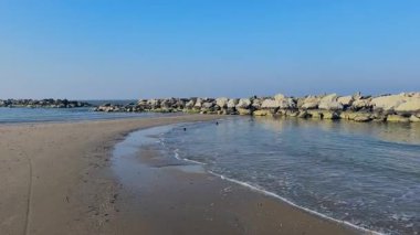 Adriyatik Denizi boyunca bir kış günü Rimini 'de boş bir plaj. Kaya dalgaları, berrak ve soğuk bir gökyüzünün altında suyun içinde duruyor. Yüksek kalite 4k görüntü